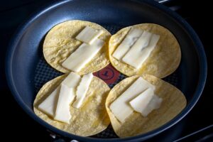 Adding cheese to the corn tortillas