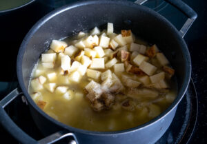 Adding the stock and potatoes to the pan