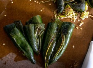 The roasted Poblanos being de-seeded and de-stemmed