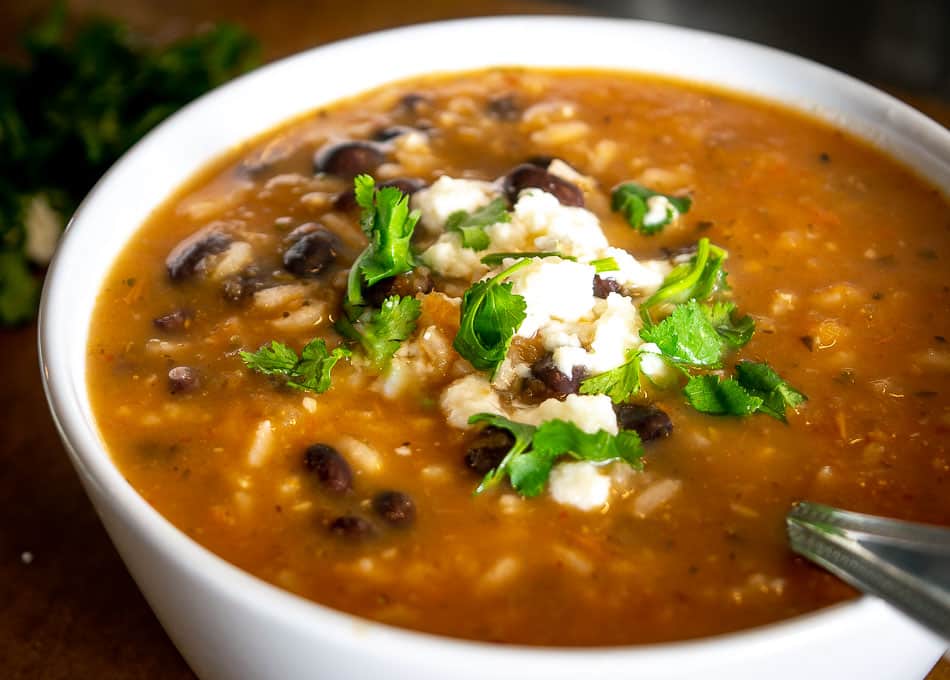 Adding Queso Fresco, cilantro, and a squeeze of lime to the soup