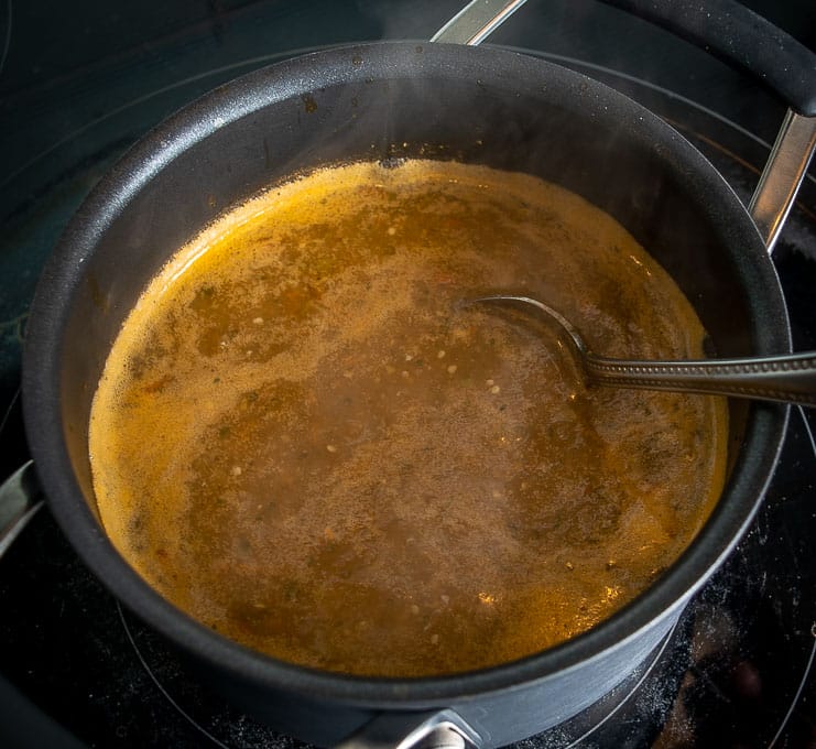 Adding stock and salt to the simmering salsa