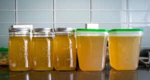 2 gallons of homemade chicken stock in mason jars and tupperware containers
