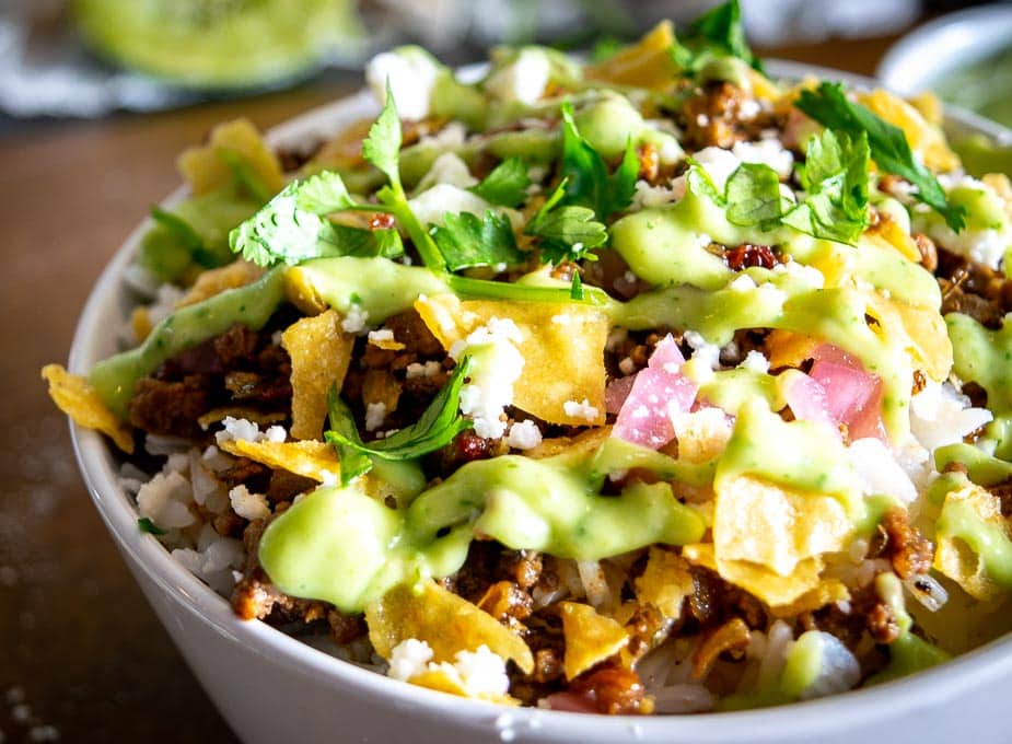 Adding crumbled tortilla chips to the ground beef bowl