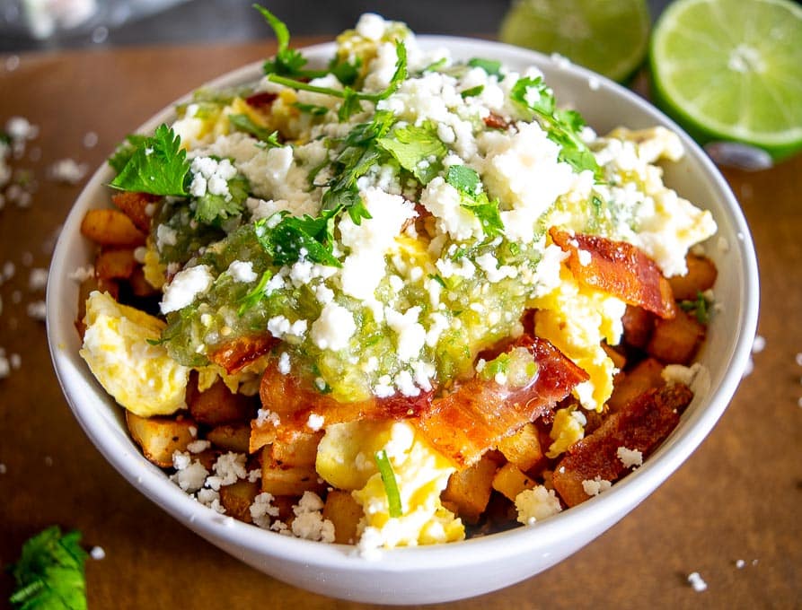 Adding the Salsa Verde, Queso Fresco, and freshly chopped cilantro to the breakfast burrito bowls