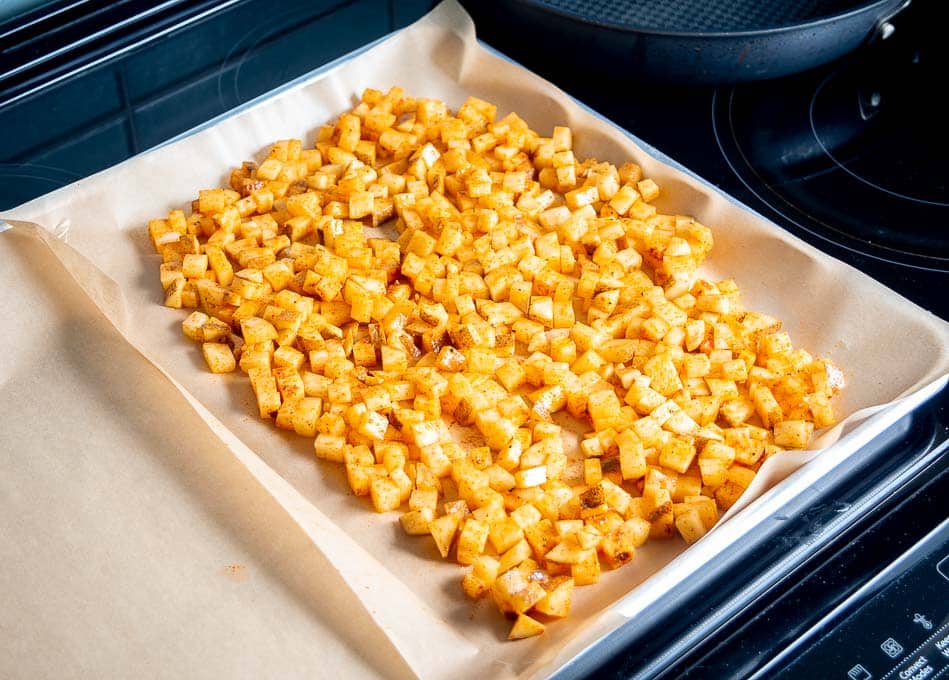 Spreading the cubed potatoes out on a baking sheet in an even layer