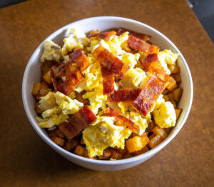 Starting to build the burrito bowl with a layer of potatoes, eggs, bacon