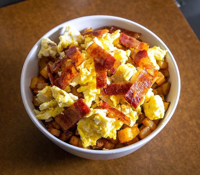 Starting to build the burrito bowl with a layer of potatoes, eggs, bacon