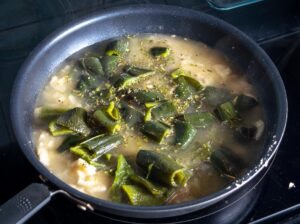 Adding roasted Poblano pieces to the onion garlic mixture in the pan