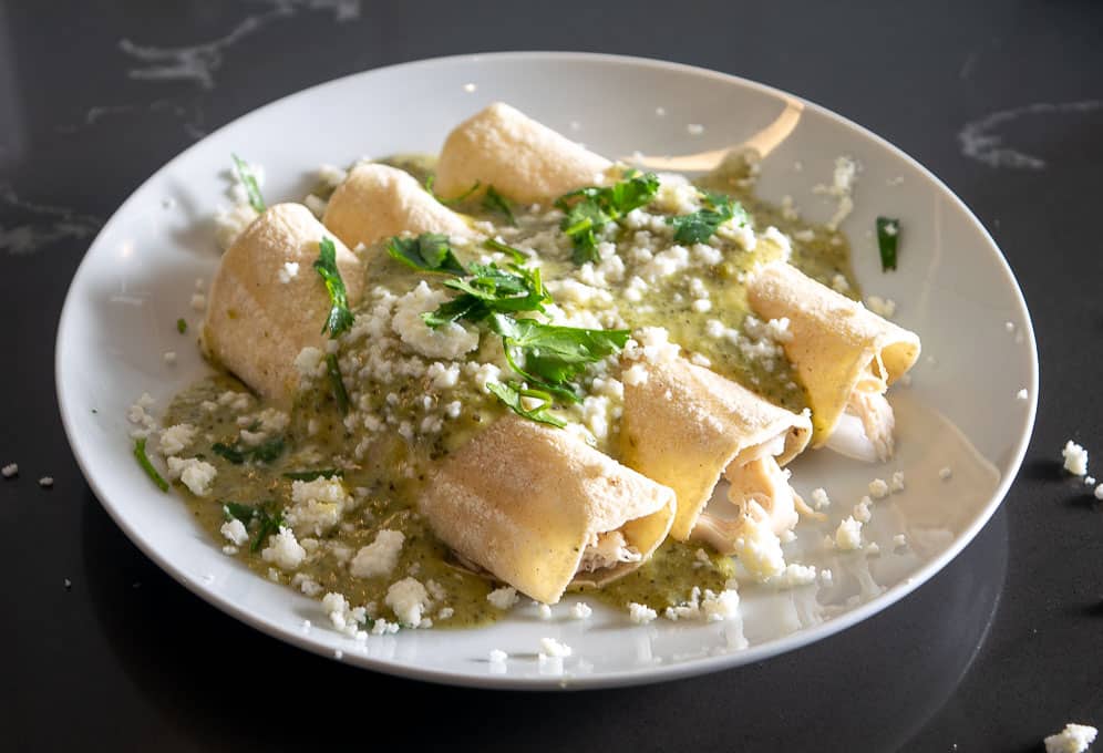 Garnishing the enchiladas with Queso Fresco, cilantro, and lime