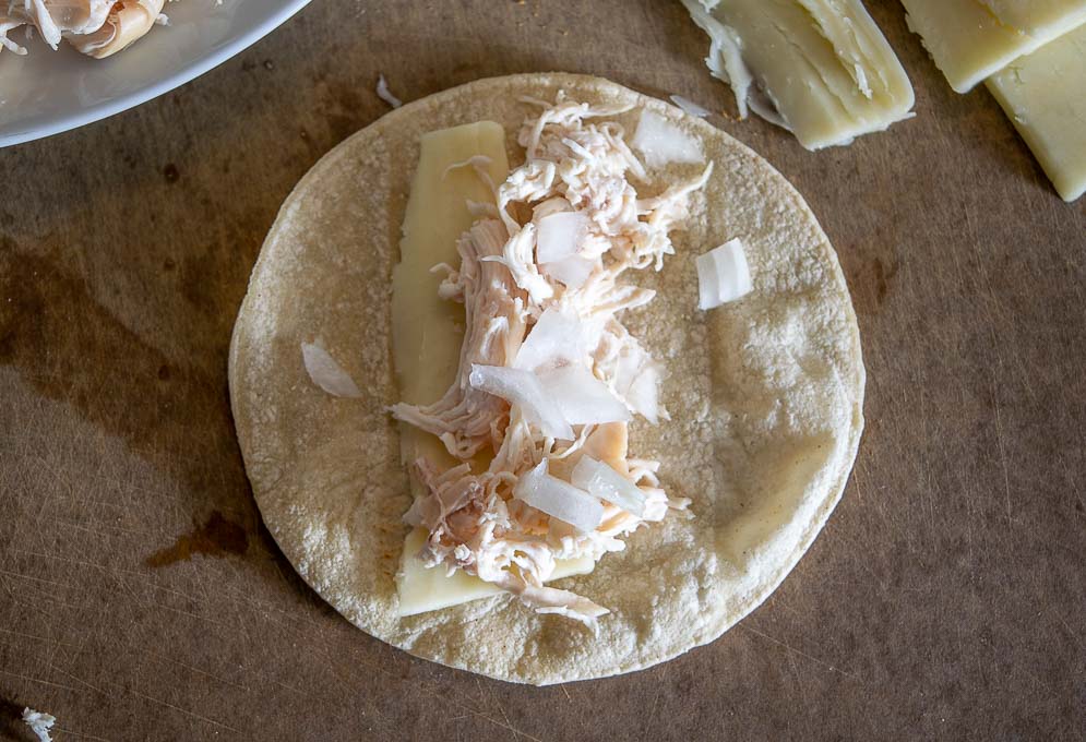 Building the enchiladas with chicken, cheese, and raw onion