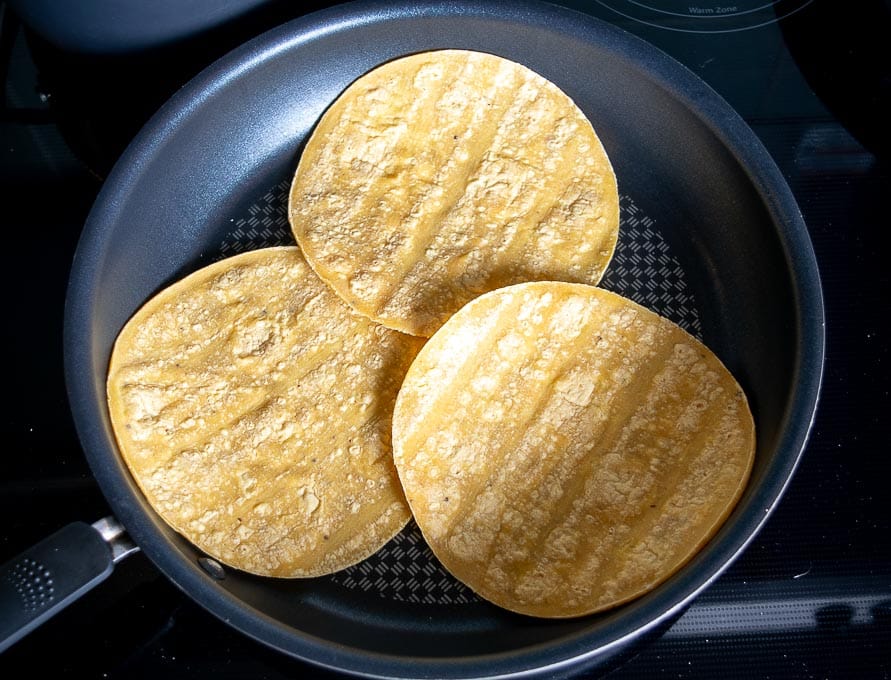 Warming up the corn tortillas in the pan for the enchiladas