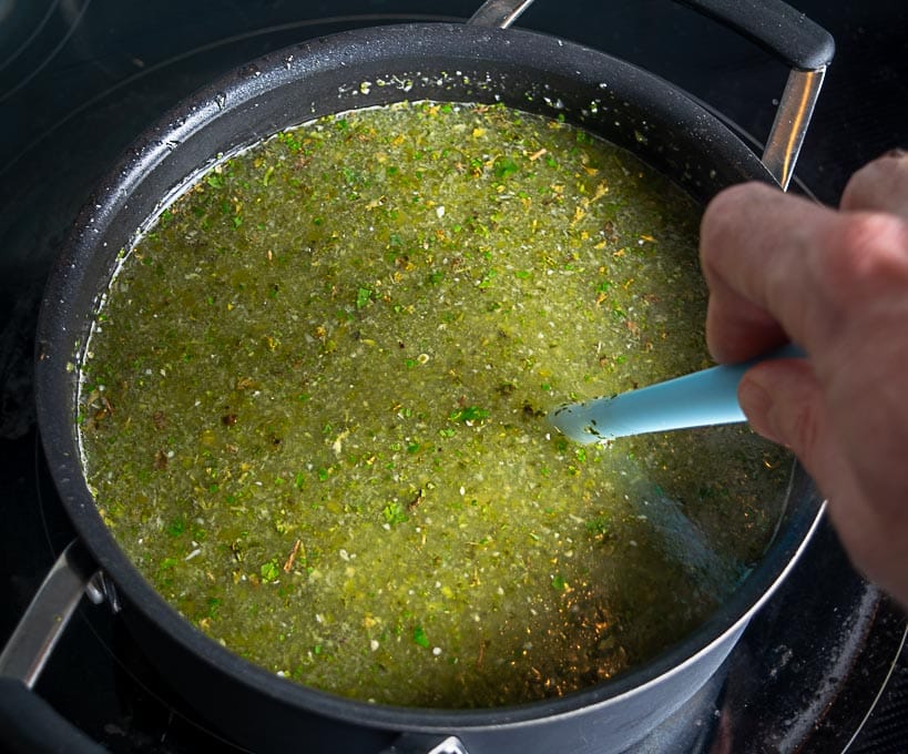 Adding broth and aromatics to the Pozole