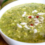 Adding Crema, black pepper, and hot sauce to the Avocado Soup