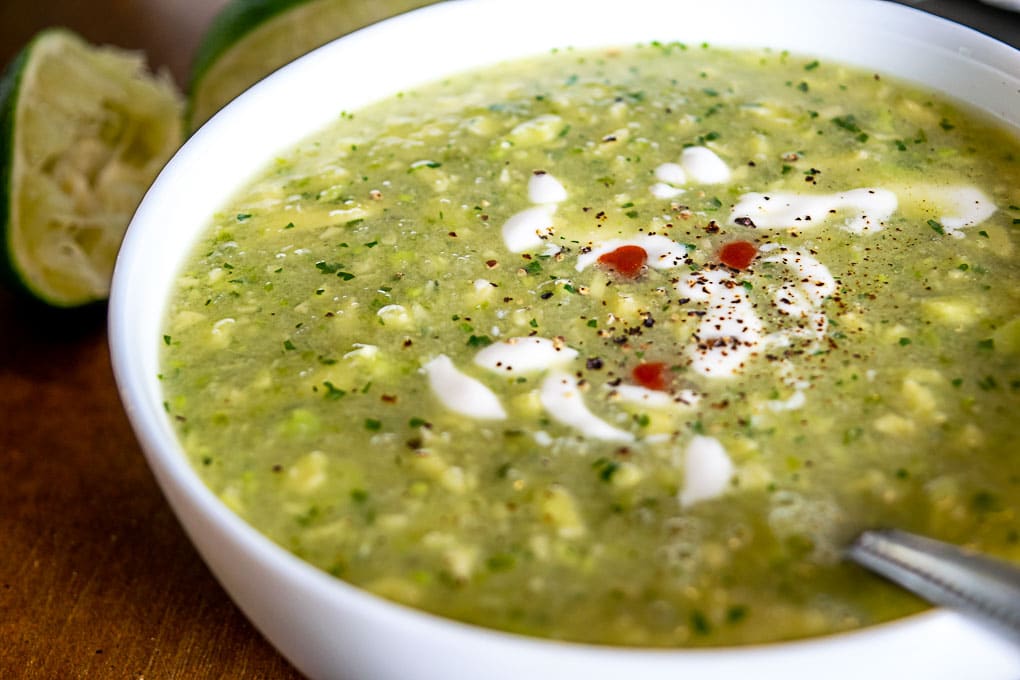 Adding Crema, black pepper, and hot sauce to the Avocado Soup