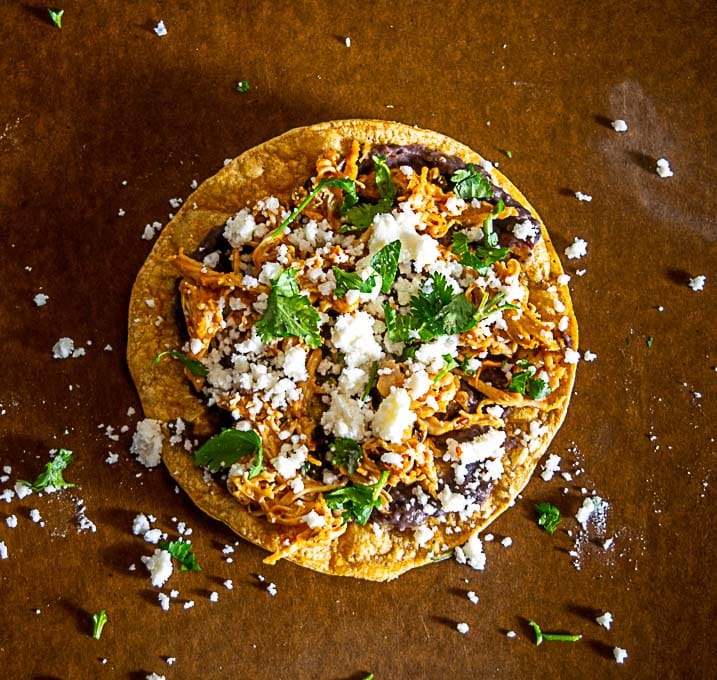 Adding queso fresco, cilantro and lime to the tostadas