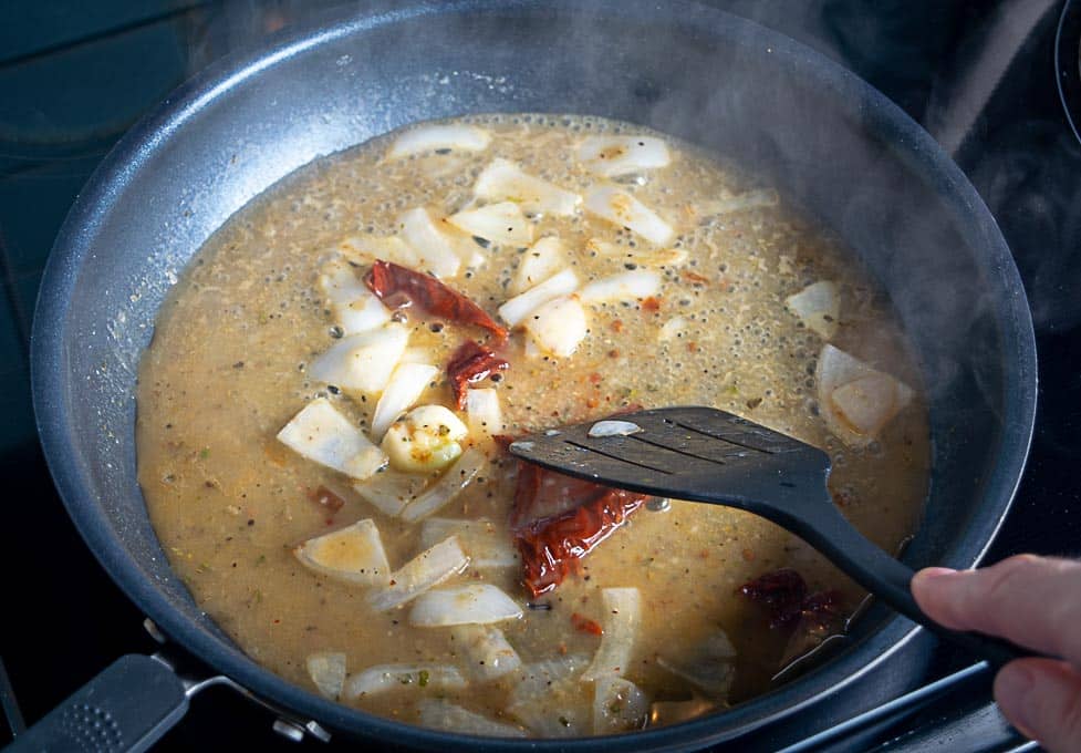 Adding stock and chipotles to the sauce