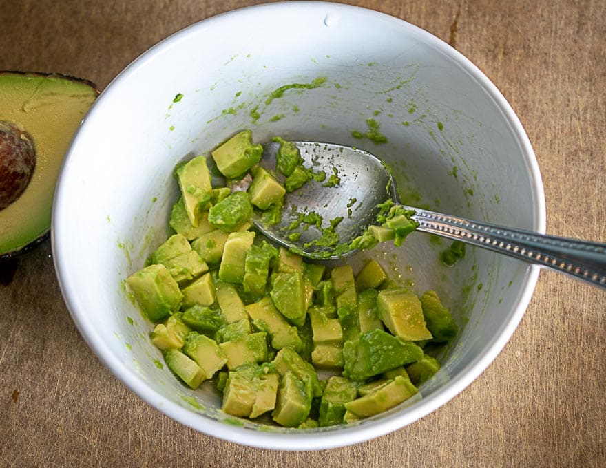Tossing diced avocado with lime juice and salt