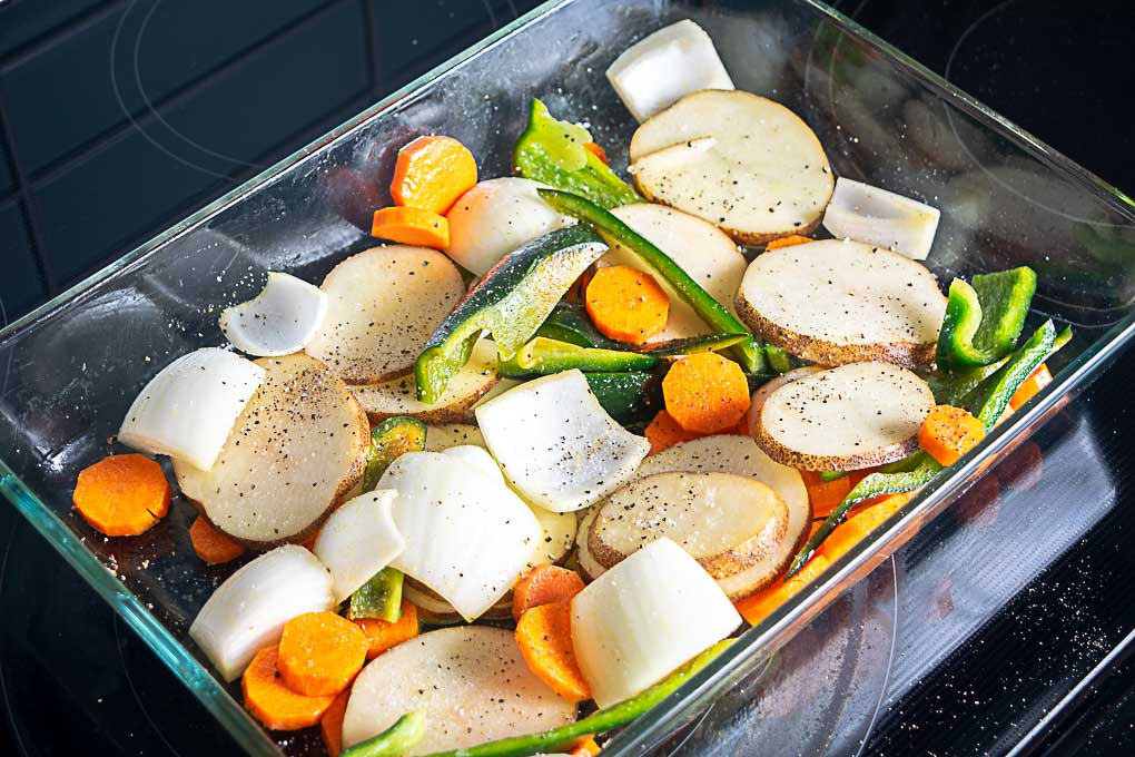 Tossing veggies in oil in the roasting pan