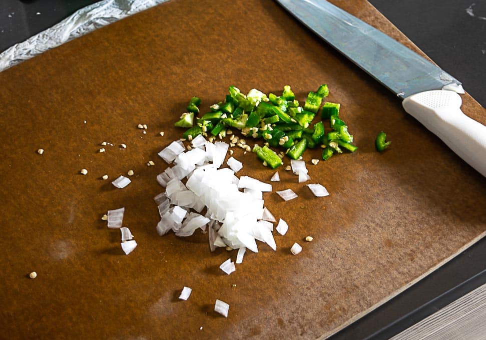 Chopping up 1-2 tablespoons of both onion and jalapeno