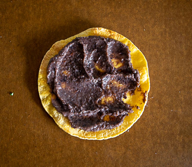 Warm crispy tostada shell with homemade refried beans