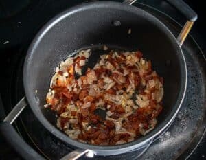 Adding chopped onion to the browned bacon pieces