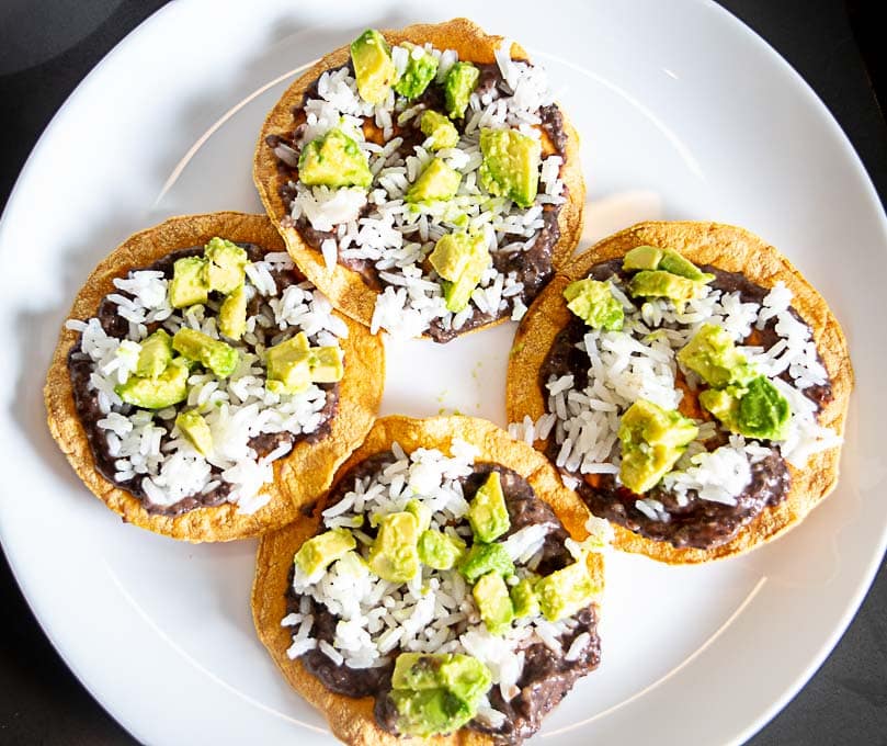Base layer of the Tostadas has beans, rice, and avocado bits