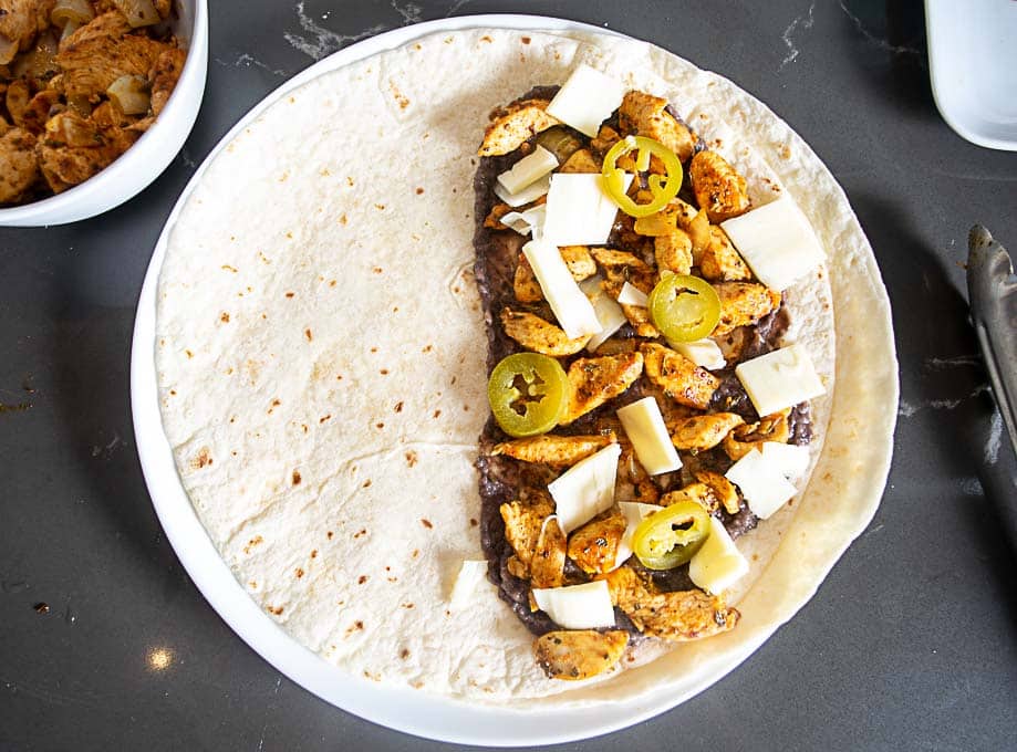 Loading up the quesadilla with beans, cheese, chicken, and pickled jalapenos