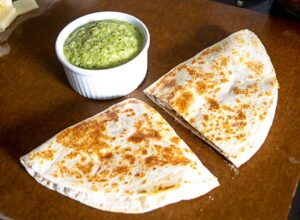 Serving up the chicken quesadilla next to a bowl full of avocado salsa verde