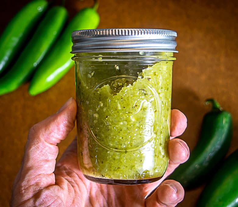 Holding jar full of jalapeno serrano hot sauce