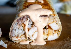 Drenching the burritos with creamy chipotle sauce