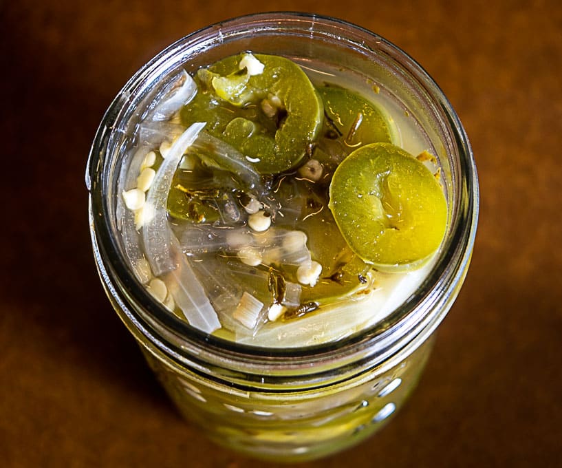 Adding the jalapeno mixture to a glass jar