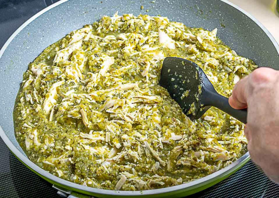 Adding shredded chicken to the chile verde sauce