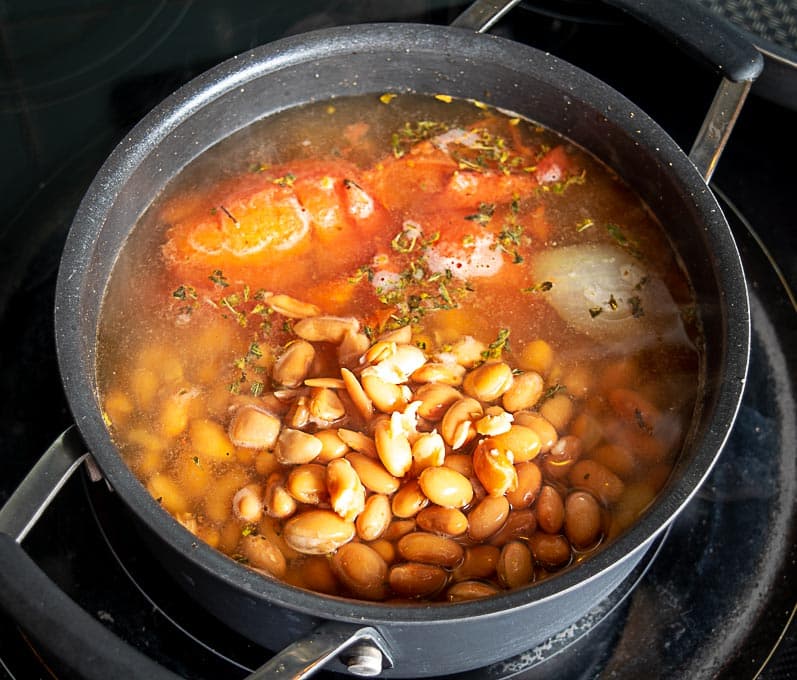 Adding the pinto beans and roasted tomatoes to the soup pot
