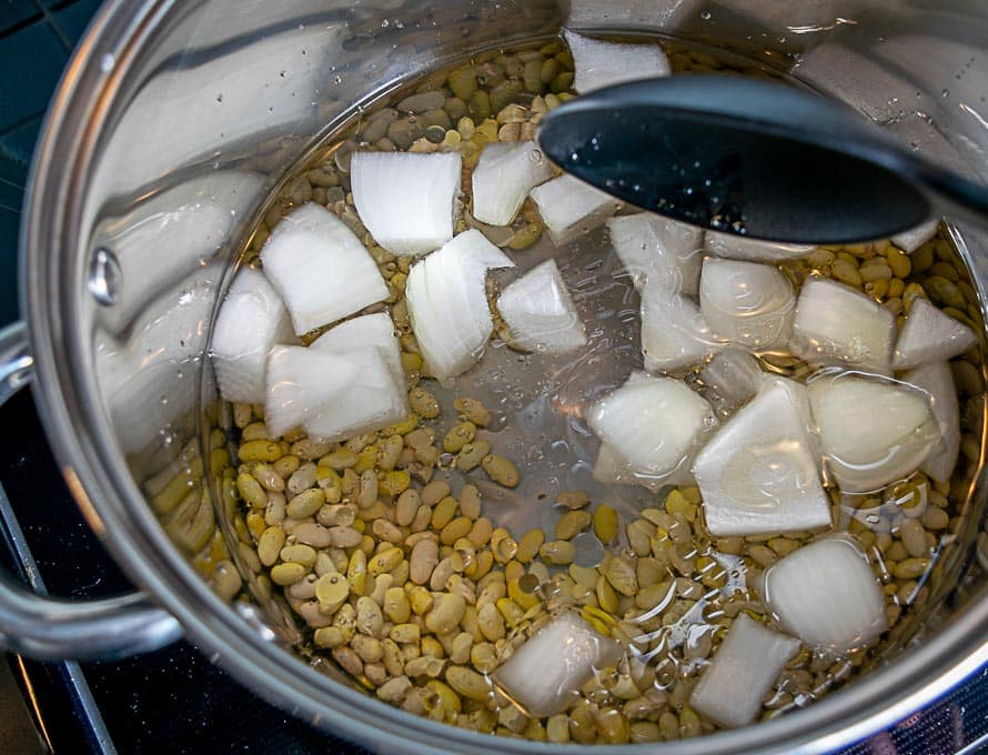 Adding onion, bacon drippings and water to the Peruano beans