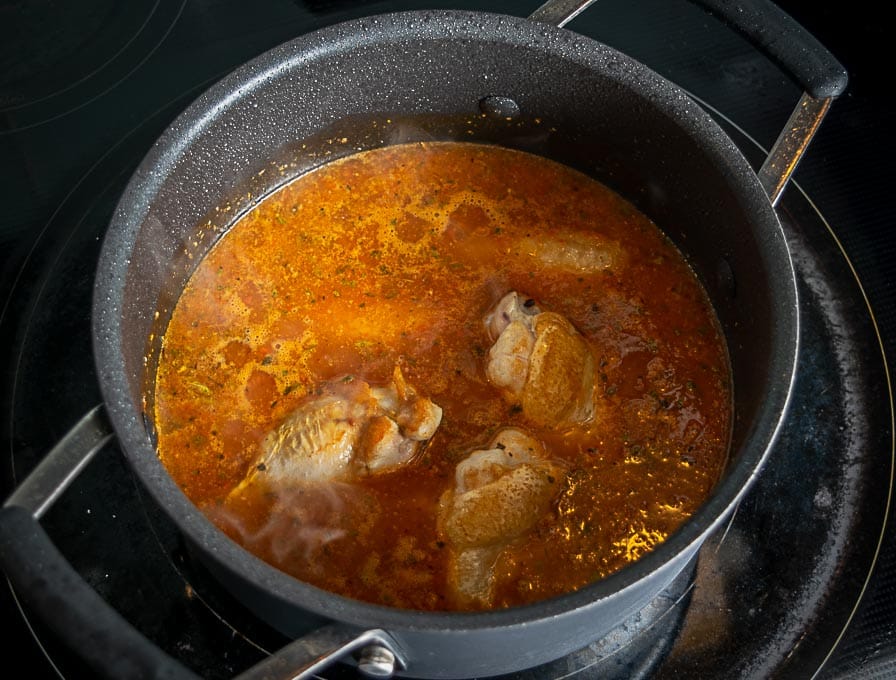 Adding the browned chicken wings to the tomato chipotle mixture