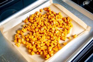 Adding cubed potatoes to a baking sheet