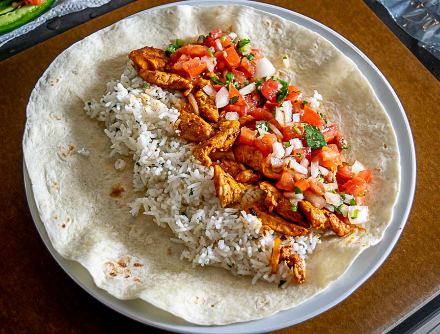 Adding rice, chicken, cheese and Pico de Gallo to the flour tortillas