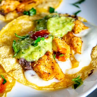 Close up of Chicken Taco drenched in Avocado Salsa Verde, freshly chopped cilantro, and a few drops of hot sauce